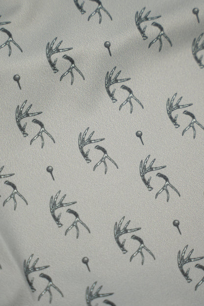 Patterned fabric featuring antlers and golf tees, showcasing the unique design of the Tees &amp; Tines Golf Polo.